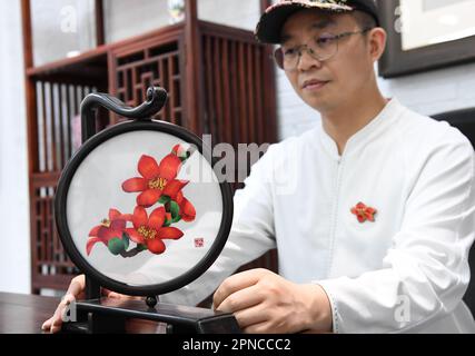 (230418) -- GUANGZHOU, 18 aprile 2023 (Xinhua) -- Wang Xinyuan presenta un pezzo di artigianato di Guangzhou ricamo su fiori di cotone di seta nel suo studio nel distretto di Liwan di Guangzhou, provincia di Guangdong della Cina meridionale, 4 aprile 2023. Il ricamo cantonese è uno dei quattro famosi ricami in Cina. Il ricamo di Guangzhou, parte del ricamo cantonese, risale alla Dinastia Tang (618-907) e ha una storia di oltre 1.000 anni. Vantando oltre 30 tipi di punti, il ricamo Guangzhou è ben noto per la composizione complicata, l'immagine vivace, i colori ricchi e lucentezza, e stili vari. Poll Foto Stock