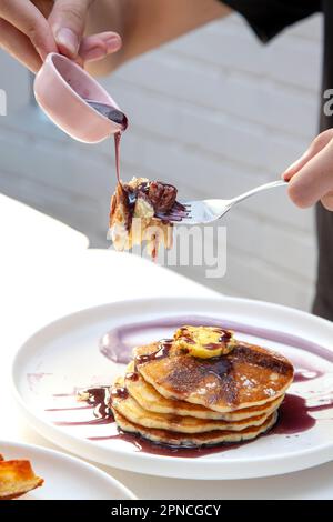Cioccolato grattugiante sulla torta tagliata in padella con una forchetta. Foto Stock