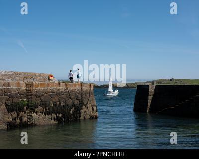 Una barca a vela che passa davanti all'ingresso del porto di Colliemore, Dublino, Irlanda. Foto Stock