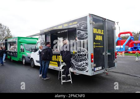 Un gruppo di persone si riunisce intorno a una varietà di camion alimentari in un parco divertimenti all'aperto Foto Stock