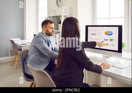 Due operatori che analizzano grafici di dati e grafici sul monitor del pc Foto Stock