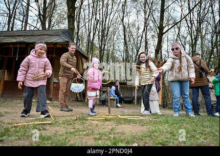 LVIV, UCRAINA - 16 APRILE 2023 - Adulti e bambini lanciano anelli durante la celebrazione pasquale al Museo di architettura popolare di Klymentii Sheptytskyi Foto Stock