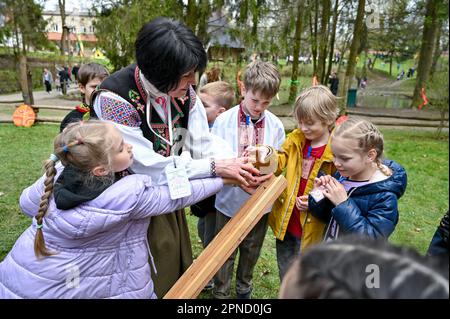 LVIV, UCRAINA - 16 APRILE 2023 - Una donna parla ai bambini durante la celebrazione pasquale al Museo di architettura popolare di Klymentii Sheptytskyi e. Foto Stock