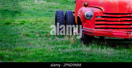 Vecchio camion da lavoro rosso funerato abbandonato in un campo verde fattoria Foto Stock