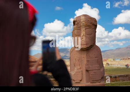 Un turista che scatta una foto con uno smartphone a un monolite a Tiwanaku, un sito archeologico precolombiano nella Bolivia occidentale. Foto Stock