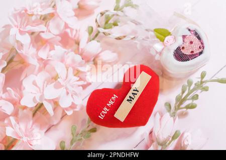 Ogni giorno è il giorno della mamma. I concetti del giorno della madre e del giorno più bello, concetto dell'amore. Cuore rosso con la lettera AMORE MAMMA con bel fiore su sfondo rosa Foto Stock