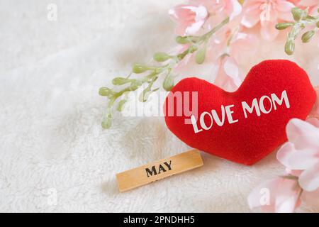 Ogni giorno è il giorno della mamma. I concetti del giorno della madre e del giorno più bello, concetto dell'amore. Cuore rosso con la lettera AMORE MAMMA con bel fiore su sfondo rosa Foto Stock