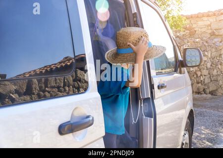 bambino sulla porta di un camper con cappello di paglia Foto Stock