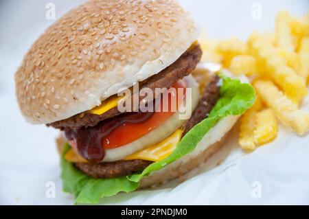 Doppio Cheeseburger servito con patate fritte Foto Stock