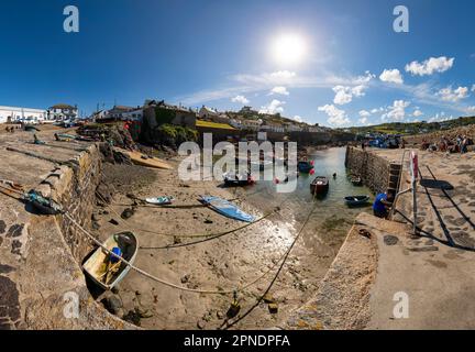 Barche da pesca ormeggiate nel porto di Coverack sulla penisola di Lizard, Cornovaglia. Un piccolo villaggio di pescatori in una giornata estiva luminosa con persone in vacanza. Foto Stock