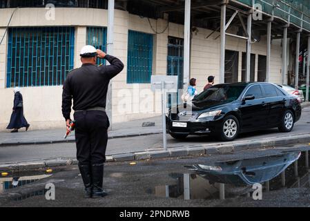 Damasco, Siria - Aprile, 2023: Ufficiale di polizia saluta un'auto di passaggio a Damasco, Siria Foto Stock