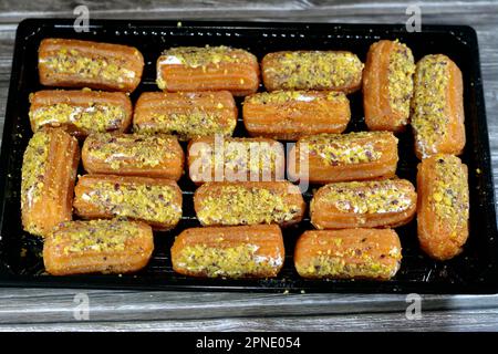 Tulumba, Bamiyeh o Balah El Sham stuffued con panna montata e coperto con pistacchi e noci, dessert fritto pastella imbevuto in sciroppo, simile Foto Stock