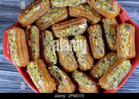 Tulumba, Bamiyeh o Balah El Sham stuffued con panna montata e coperto con pistacchi e noci, dessert fritto pastella imbevuto in sciroppo, simile Foto Stock