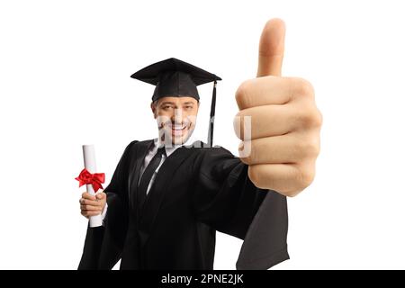 Uomo in una abito di laurea in possesso di un diploma e mostrando pollici isolati su sfondo bianco Foto Stock