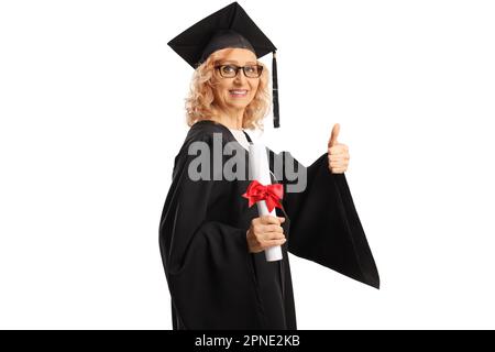 Donna matura in un abito di laurea in possesso di un diploma e mostrando pollici isolato su sfondo bianco Foto Stock