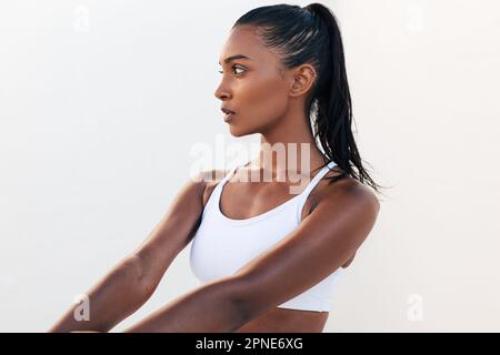 Donna snella che guarda lontano rilassarsi durante l'allenamento in palestra all'aperto. Giovane donna rilassante indossando un abito da fitness bianco. Foto Stock