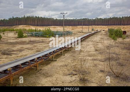 Trasportatore a nastro industriale in una fossa di sabbia Foto Stock