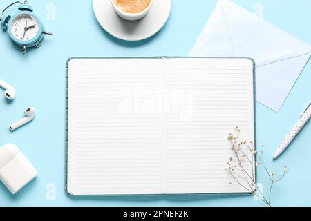 Composizione con notebook, busta, orologio e auricolari su sfondo blu Foto Stock