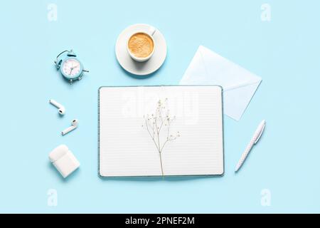 Composizione con notebook, tazza di caffè, orologio e auricolari su sfondo blu Foto Stock