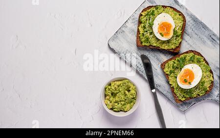 Fotografia del cibo bianco di panino con pane di segale, uova, avocado, insalata di crescione, lime, toast, colazione, dieta Foto Stock