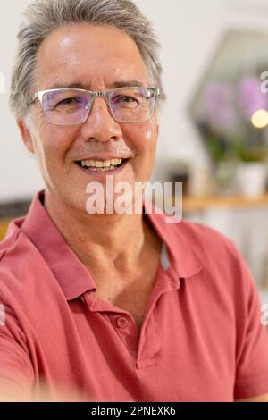 Primo piano ritratto di uomo anziano caucasico sorridente indossando occhiali a casa, copia spazio Foto Stock