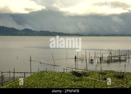 Un allevamento ittico e lo scenario del lago Tondano sono fotografati in primo piano in un giacinto d'acqua, una specie di piante d'acqua dolce invasive, a Minahasa, Sulawesi settentrionale, Indonesia. L’acquacoltura ha un grande potenziale per nutrire e nutrire la crescente popolazione mondiale. Ma la crescita deve essere sostenibile, secondo l'ultimo rapporto della FAO intitolato "lo Stato della pesca e dell'acquacoltura nel mondo 2022. Verso la trasformazione del blu". Nel 2020, la produzione globale di acquicoltura ha raggiunto il record di 122,6 milioni di tonnellate, per un valore complessivo di 281,5 miliardi di dollari. L'Asia continuò a dominare l'acquacoltura mondiale. Foto Stock