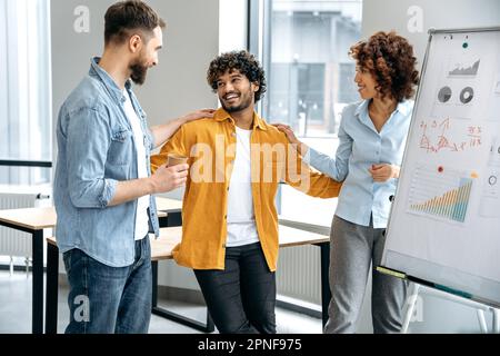 Gruppo motivato di colleghi multirazziali, team creativo di top manager, stare in un ufficio moderno vicino a una lavagna bianca, comunicare, sono soddisfatti dei risultati del lavoro, sorriso Foto Stock