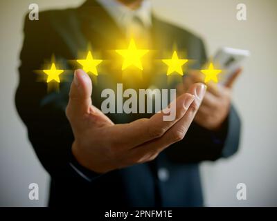 Mano di uomo d'affari che dà cinque stelle per la sua piena soddisfazione. Fornendo una valutazione a cinque stelle. Valutazione dei servizi e clienti, clienti, imprese evaluatio Foto Stock