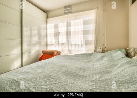 una camera da letto con un letto, comò e finestra sullo sfondo che ha luce del sole che splende attraverso le persiane sulle finestre Foto Stock