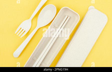 Cucchiai, forcelle e bacchette in plastica su sfondo giallo. Foto Stock