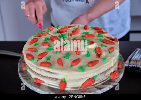 Le mani delle donne tagliano la torta di compleanno decorata sul tavolo nero Foto Stock