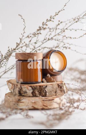 Un set di candele di soia in un vaso di vetro marrone con un coperchio di  legno. Candela aromatica bruciante. Accendi le candele con un fiammifero.  Accogliente e igge. Aromaterapia Foto stock 