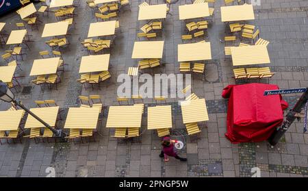 Monaco, Germania. 19th Apr, 2023. Una donna passa davanti a un bar vuoto sul marciapiede. Credit: Peter Kneffel/dpa/Alamy Live News Foto Stock