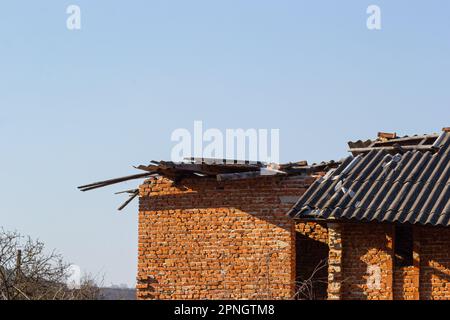 Tetto distrutto di casa di mattoni. Casa distrutta dopo una tempesta o come risultato di conchiglie. Foto Stock