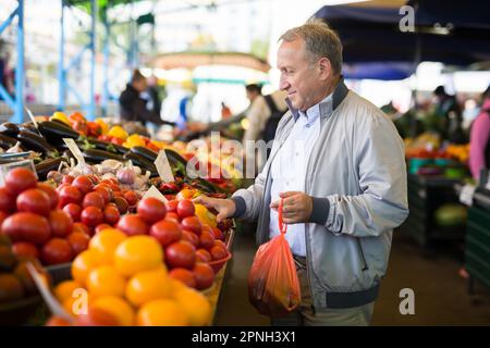 Uomo che acquista peperoni in gregrocery Foto Stock