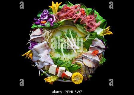 Hot pot coreano con pesce crudo su sfondo nero Foto Stock