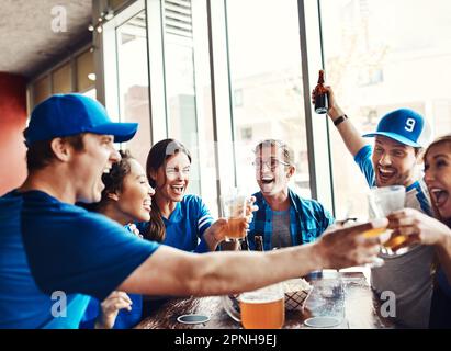 Sarà un gioco abbastanza. un gruppo di amici che beve birra mentre si guarda una partita sportiva in un bar. Foto Stock