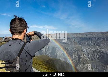 Dettifoss, Islanda - 2021 agosto: I turisti scattano foto ad un arcobaleno unico e raro sopra la cascata di Dettifoss, con acque massicce spruzzate e stea Foto Stock