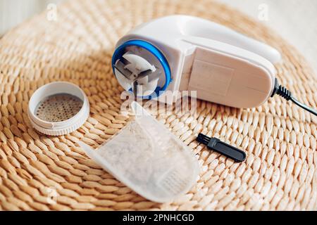 Rimuovere il lanugine dopo aver rasato il prodotto utilizzando una piccola spazzola. Contenitore e rasoi pieni di residui e sporcizia. Moderno strumento per la casa Foto Stock