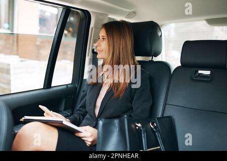Ambizione in movimento costante. una donna d'affari matura che guarda con attenzione alla finestra di un'auto. Foto Stock