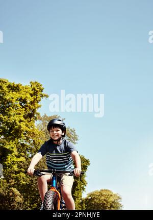 I bambini imparano attraverso la loro esplorazione. un giovane ragazzo che cavalca la bicicletta attraverso il suo quartiere. Foto Stock