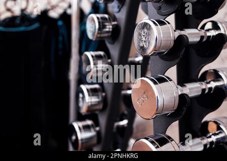 Primo piano con moderni manubri in metallo. Attrezzature sportive in palestra o nel centro fitness. Sfondo chiaro. Spazio libero per il testo. Foto Stock