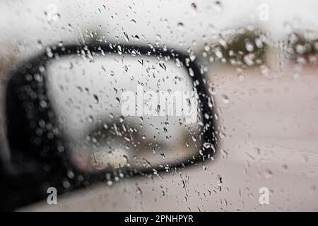 gocce di pioggia sullo specchietto destro della vettura, scarsa visibilità. Maltempo Foto Stock