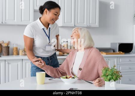 lavoratore sociale multirazziale felice che tiene le mani di donna pensionato thankful Foto Stock