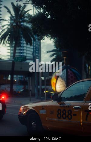 Un taxi giallo che guida su una strada con uno skyline della città sullo sfondo Foto Stock