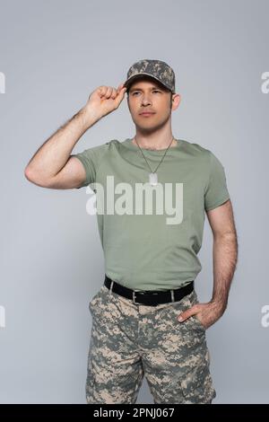 soldato patriottico in t-shirt regolabile berretto militare durante il giorno del memoriale isolato sul grigio Foto Stock