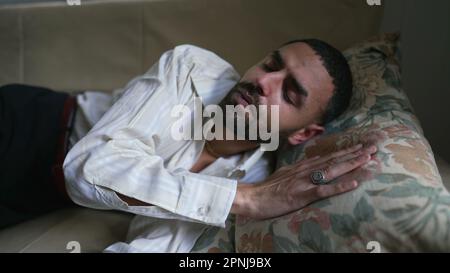 Uomo sdraiato sul divano dopo il lavoro di giorno. Un uomo arabo del Medio Oriente che si rilassa a casa dopo una lunga giornata faticosa Foto Stock