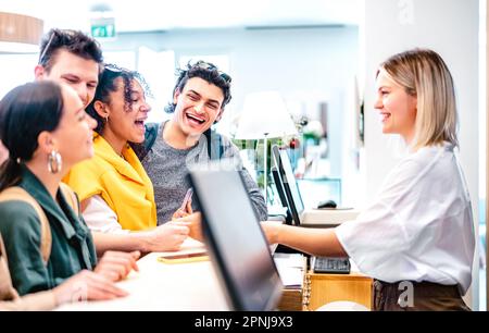 Giovani amici diversi divertirsi alla reception dell'hotel di lusso al momento del check-in - concetto di stile di vita di viaggio con persone felici in attesa alla pensione d Foto Stock