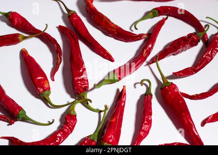 I peperoncini rossi maturi sono posti su una superficie bianca Foto Stock