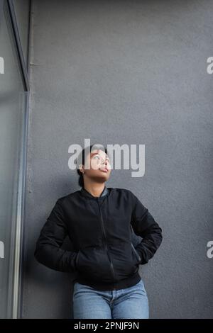 donna multirazziale con problema mentale in piedi vicino alla parete della costruzione all'aperto, immagine di riserva Foto Stock